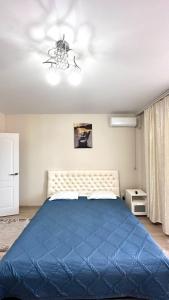 ein Schlafzimmer mit einem blauen Bett und einem Kronleuchter in der Unterkunft 1 комнатная драмтеатр 1bedroom apartment in Öskemen