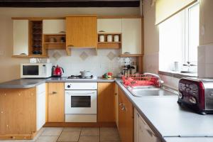 a small kitchen with a sink and a microwave at Granary Cottage at Scolton Cottages - Indoor pool in HAW