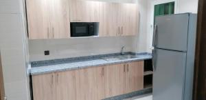a kitchen with a white refrigerator and a sink at appartement pres de l aéroport de tanger in Tangier