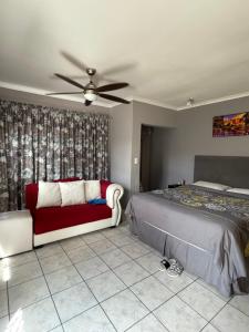 een slaapkamer met een bed, een bank en een ventilator bij Zoe & Saint in Kaapstad