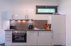 a kitchen with white appliances and a window at Bewusstsein - Modernes Apartment mit Terrasse, Walk-In-Dusche & Wellnesszugang in Krakow am See