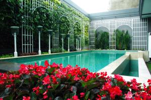 a swimming pool with red flowers in front of a building at d'Primahotel Bandung in Bandung