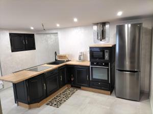 a kitchen with black cabinets and a stainless steel refrigerator at Le Gite du Planey in Plainemont