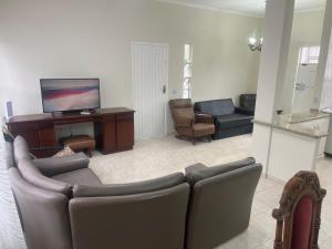 un salon avec un canapé, une télévision et des chaises dans l'établissement Casa Centro de Bertioga - SP terrea 300 metros da praia - Marcondes 05, à Bertioga