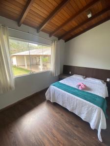 a bedroom with a bed and a large window at Casas Regiao de Pedra Azul Cverde in Domingos Martins