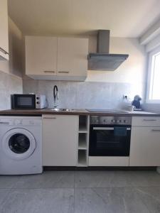 a kitchen with a stove and a washing machine at Top appart V9 in Village-Neuf +4 photos