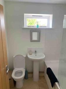 a white bathroom with a toilet and a sink at Beach Walk in Radipole
