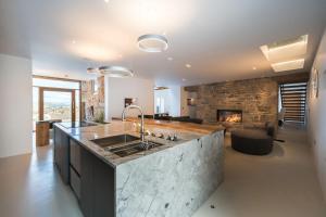 a kitchen with a stone fireplace and a large kitchen island at Carden Laithe By Birch Stays in Skipton