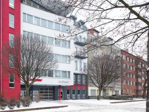 un edificio rojo y blanco con árboles delante de él en mk hotel berlin en Berlín