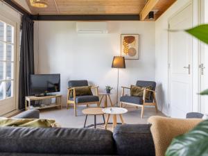 a living room with a couch and chairs and a tv at Holiday Home Natuurlijk de Veenhoop by Interhome in De Veenhoop