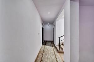 an empty hallway with white walls and wooden floors at Hotel O HM & Restaurant in Begās