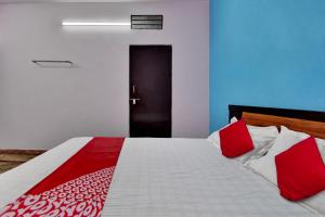 a bedroom with a bed with red and white pillows at Hotel O HM & Restaurant in Begās