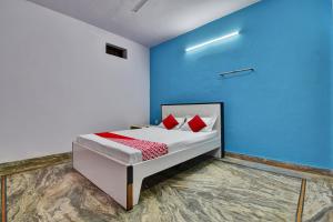 a bedroom with a bed with blue walls and red pillows at Hotel O HM & Restaurant in Begās