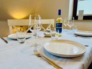 a table with plates and glasses and a bottle of wine at App Blaue Welle in Morsum