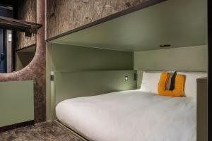 una camera da letto con un grande letto bianco con cuscini arancioni di Pods by The Usual Rotterdam a Rotterdam