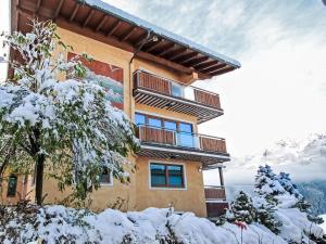 a building in the snow with mountains in the background at Apartment Panorama Dachstein by Interhome in Rohrmoos