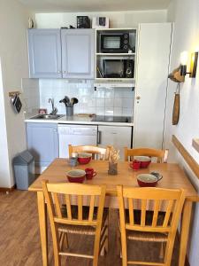 cocina con mesa de madera con sillas y comedor en Appartement 5 personnes - Lumière des Neiges A 209, en Valmeinier 2 fotos más