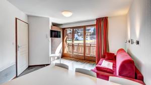 a living room with a red couch and a balcony at Vacancéole - Résidence Grand Massif in Morillon