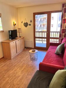 Una sala de estar con un sofá rojo y un televisor. en Appartement 5 personnes - Lumière des Neiges A 209, en Valmeinier