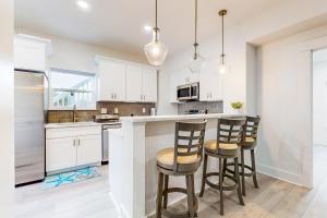 a kitchen with white cabinets and a bar with stools at Bahia Beauty - 1st Floor in Navarre