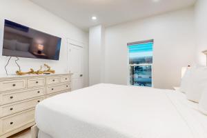 a white bedroom with a large bed and a tv at Bahia Beauty - 1st Floor in Navarre