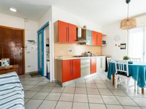 une cuisine avec des armoires orange et une table. dans l'établissement Apartment Casa dei Limoni by Interhome, à Arma di Taggia