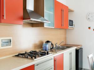 La cuisine est équipée d'armoires orange et d'un four avec plaques de cuisson. dans l'établissement Apartment Casa dei Limoni by Interhome, à Arma di Taggia