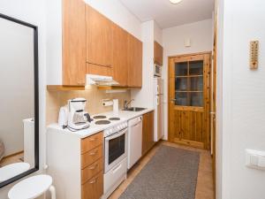 a small kitchen with white appliances and wooden cabinets at Holiday Home Rautulampi g14 by Interhome in Saariselka