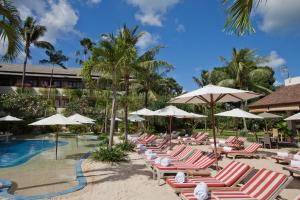a group of lounge chairs and umbrellas next to a pool at Blu-Zea Resort by Double-Six in Seminyak