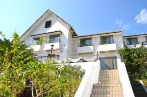 a white building with trees in front of it at Gardenvilla Shirahama in Shimoda