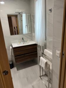ein Badezimmer mit Waschbecken und Spiegel in der Unterkunft Apartamentos Turísticos SANTA APOLONIA 62 in Avilés