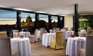 a restaurant with white tables and chairs with a view at Atlante Star Hotel in Rome
