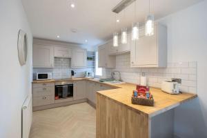 a kitchen with white cabinets and a wooden counter top at Easter Cottage -4 Bed Converted Barn Cottage in Turriff