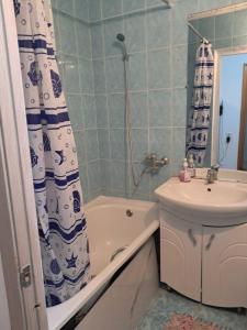 a bathroom with a sink and a tub and a shower curtain at 1 комн квартира рн Сазда БЦ МИР в Центре in Aktobe
