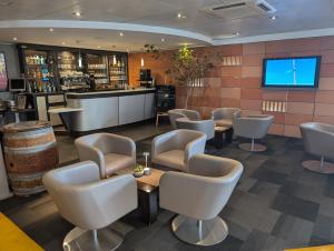 a restaurant with a bar with chairs and a tv at Hotel L'Hotan in Portet-sur-Garonne