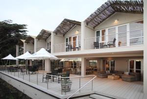 una casa con terraza con mesas y sombrillas en Abalone Guest Lodge, en Hermanus