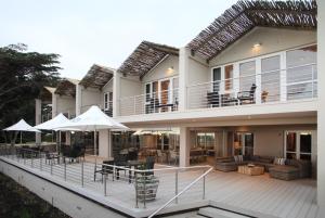 una casa con terraza con mesas y sombrillas en Abalone Guest Lodge en Hermanus