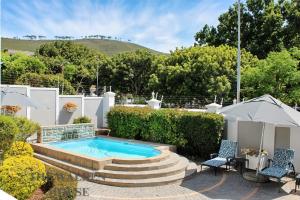 a swimming pool in a garden with two chairs and a table at The Walden House in Cape Town