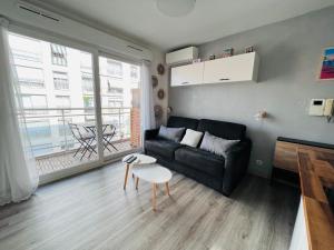 a living room with a black couch and a table at Studio terrasse et parking privé in Nice