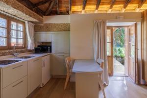 a kitchen with white cabinets and a table and chairs at Quinta da Janeca in Vila Pouca de Aguiar