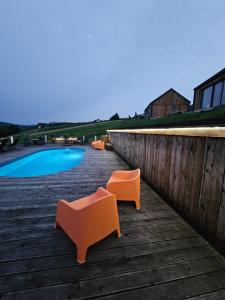 a row of orange chairs sitting on a deck next to a pool at Stodoły w Bieszczadzie domy SPA z basenem i widokiem na góry in Polańczyk +89 photos