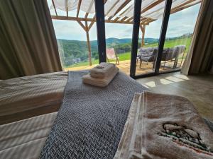 a bedroom with a bed with a large glass window at Stodoły w Bieszczadzie domy SPA z basenem i widokiem na góry in Polańczyk