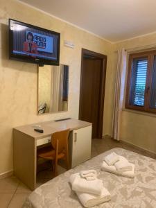 a room with a bed with a desk and a tv on the wall at Scilla e Cariddi in Scilla
