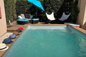 a swimming pool with an umbrella and chairs and a table at La Villa Nawengo in Le Thor