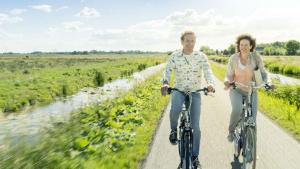 a man and a woman riding bikes down a road at Bed and Breakfast De Dijk in Zuid-Beijerland