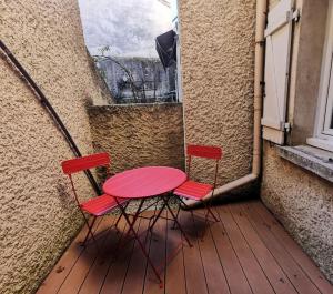 two red chairs and a pink table on a balcony at Cozy deux pieces, terrasse, en centre ville in Valence