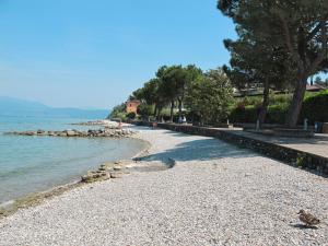 a rocky beach with trees and the water at Holiday Home Eden-3 by Interhome in San Felice del Benaco