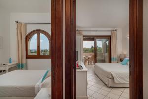 a hotel room with two beds and a balcony at Hotel Mariposas in Villasimius
