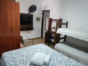 a bedroom with a bed and a tv and a bedskirts at Colonial Praiano in Guarapari