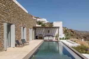 a villa with a swimming pool next to a building at Villa Maera Maximus in Mikonos